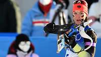 Ein Biathletin geht gerade mit ihrem Gewehr in den Anschlag