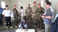 Zwei deutsche Soldaten begutachten zusammen mit sieben weiteren kurdischen Männern den Boden der neuen Küche
