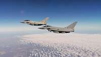 Zwei Kampfflugzeuge vom Typ Eurofighter fliegen nah beieinander.