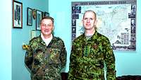 Zwei Soldaten stehen nebeneinander in einem Büro und schauen freundlich in die Kamera.