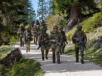 Rekrutinnen und Rekruten marschieren im Gebirge Eine Gruppe von Soldaten laufen mit Waffen einen Weg im Gebirge entlang.