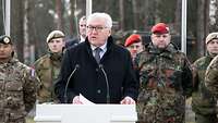 Bundespräsident Frank-Walter Steinmeier steht vor Soldaten verschiedener Länder an einem Rednerpult.