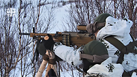 Zwei Soldaten in weißer Uniform schießen stehend im Schnee mit braunen Maschinengewehren.