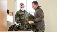 Der Soldat erklärt dem Zivilisten die Ausrüstung und die Uniform.