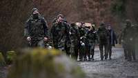 Eine der beiden Gruppen marschiert samt Gepäck durch den Wald. 
