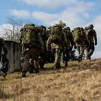 Eine Teilnehmergruppe marschiert in Schützenreihe den Hügel hinauf.