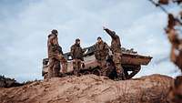 Eine Gruppe von Soldaten steht vor einem Bergepanzer Büffel und unterhält sich
