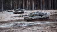 Zwei Leopard Kampfpanzer stehen auf einer offenen Freifläche