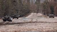 Mehrere Kampfpanzer im offenen Gelände überwachen sich gegenseitig
