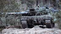 Ein Kampfpanzer steht in Stellung. Zwei Männer der Besatzung sind über der Luke zu sehen.