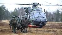 Soldaten tragen einen Verwundeten zum Hubschrauber.