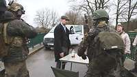 Soldaten und Zivilisten stehen auf einer Brücke und verhandeln, zwischen ihnen ein Tisch.