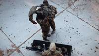 Ein Soldat legt mit Hilfe eines zweiten Soldaten seine Schutzwest ab