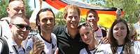 Prinz Harry lächelt mit deutschen Fans im Arm