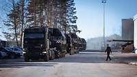Schwerlasttransport mit der Panzerhaubitze 2000 Lastkraftwagen, mit Panzerhaubitzen auf dem Auflieger, stehen in Reihe auf einer Straße. Ein Soldat steht gegenüber