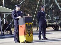 Oberstleutnant Dobrindt hält eine Rede Zwei Soldaten stehen auf einem Platz. Einer steht hinter einem Pult und hält eine Rede.