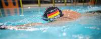 Trainieren für die Invictus Games 2022 Ein Mann schwimmt mit Deutschland-Badekappe in einem Schwimmbecken.