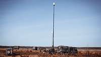 Mehrere Militärfahrzeuge stehen im Gelände. Eine Antennenanlage steht in der Mitte.