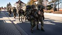 Mehrere Soldaten tragen einen verletzten Kameraden auf einer Trage auf den Schultern.