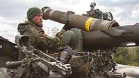Aus der Dachluke eines Panzers richtet ein Soldat eine Panzerabwehrwaffe ein.