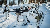 Zwei Soldaten stehen mit dem G36 im Anschlag und an den Skistöcken abgestützt im verschneiten Gelände