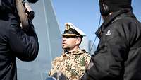 Ein Marinesoldat in sandfarbener Jacke und mit weißer Schirmmütze.