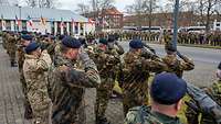 Soldaten sind zum Übergabeappell auf einem betonierten Platz angetreten und grüßen militärisch.