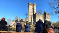 Die Teilnehmer sitzen auf einer Bank und blicken auf eine Burg