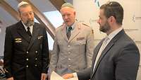 Ein Rabbiner zeigt zwei Soldaten ein gerolltes Schriftstück.
