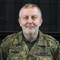 Ein Soldat in Uniform steht vor einem LKW