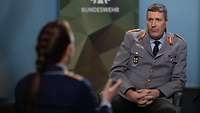 Generalinspekteur Markus Laubenthal sitzt einer Soldatin gegenüber und spricht mit ihr.