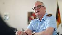Generalinspekteur Zorn sitzt an einem Tisch und spricht mit einer Person