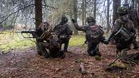 Mehrere Soldaten bewegen sich durch den Wald.