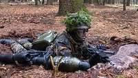 Soldat liegt auf dem Waldboden.