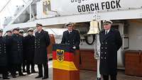 Mehrere Männer in Uniform stehen auf dem Deck eines Segelschiffs.