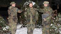 Zwei Soldaten schlagen einem weiteren Soldaten auf die Schulter.