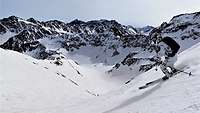 Ein Soldat fährt auf Skiern bei Sonne einen verschneiten Berg hinunter.