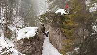 Ein Soldat steht mitten in einem Felsen in einer verschneiten Waldschlucht.