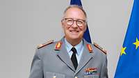 Beförderung von Prof. Dr. Horst-Peter Becker Ein Soldat und die Ministerin stehen vor drei Flaggen