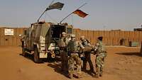 Eine britische Soldatin und drei deutsche Soldaten heben eine Trage in ein Fahrzeug