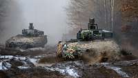 Mehrere Panzer fahren in sehr schwerem Gelände.