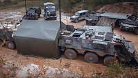 Zwei Transportpanzer stehen am aufgebauten Kompaniegefechtsstand auf einer Lichtung