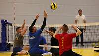 Mehrere Männer spielen Sitzvolleyball