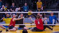 Sportler aus verschiedenen Ländern spielen Sitzvolleyball.
