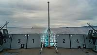 Auf dem Flugdeck der Fregatte stehen ein Flaggenstock und zwei schwere Maschinengewehre
