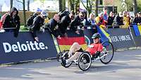Ein deutscher Sportler im Liegerad fährt auf einer betonierten Straße an Fans vorbei.