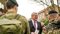 Ein Zivilist im Anzug spricht mit Soldaten, die vor ihm stehen.
