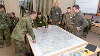 Soldaten aus verschiedenen Nationen stehen um einen Tisch mit einer Landkarte.