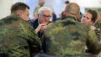 An einem Tisch sitzen drei Soldaten und der Bundespräsident