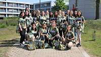 Eine Gruppe junger Frauen gekleidet in Polygonfarbenen T-shirts stehen vor einem Gebäude.
